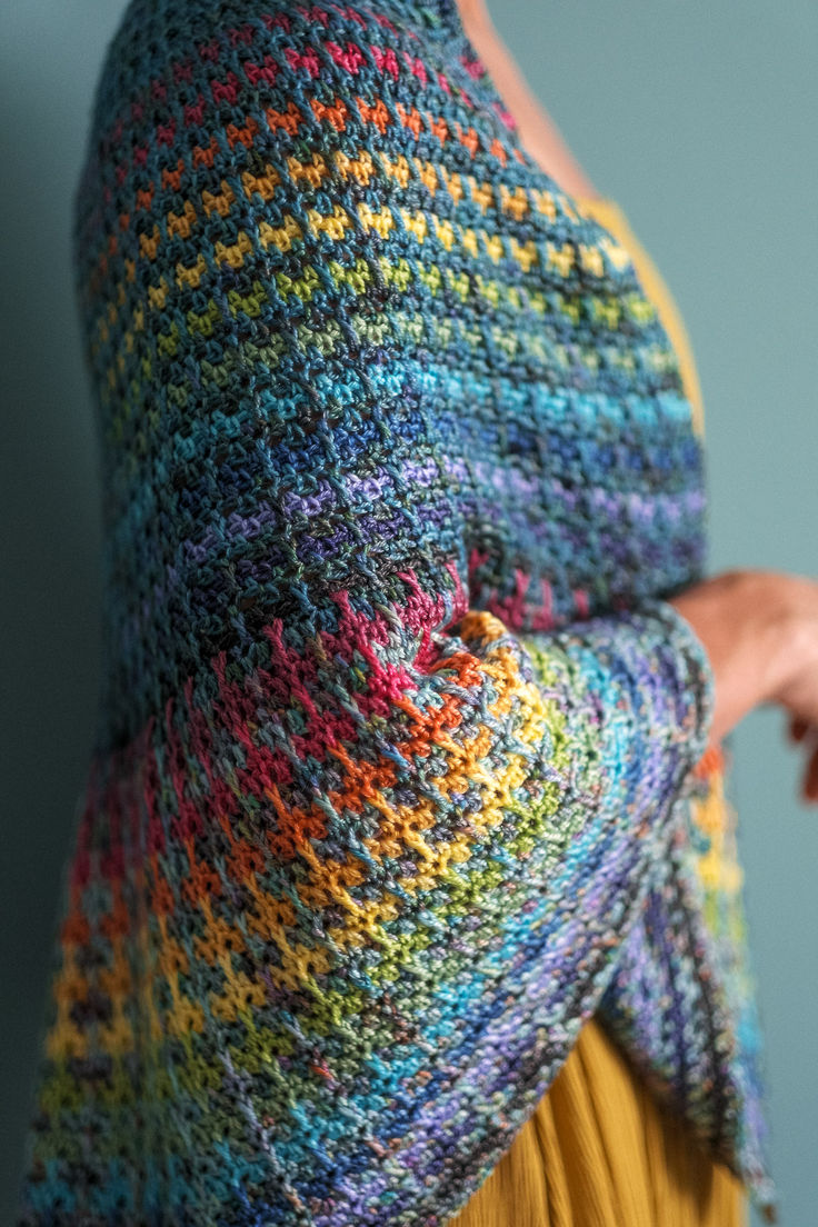 a woman wearing a multicolored knitted shawl