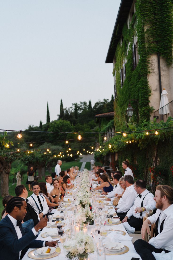 a group of people sitting around a long table with food and drinks in front of them