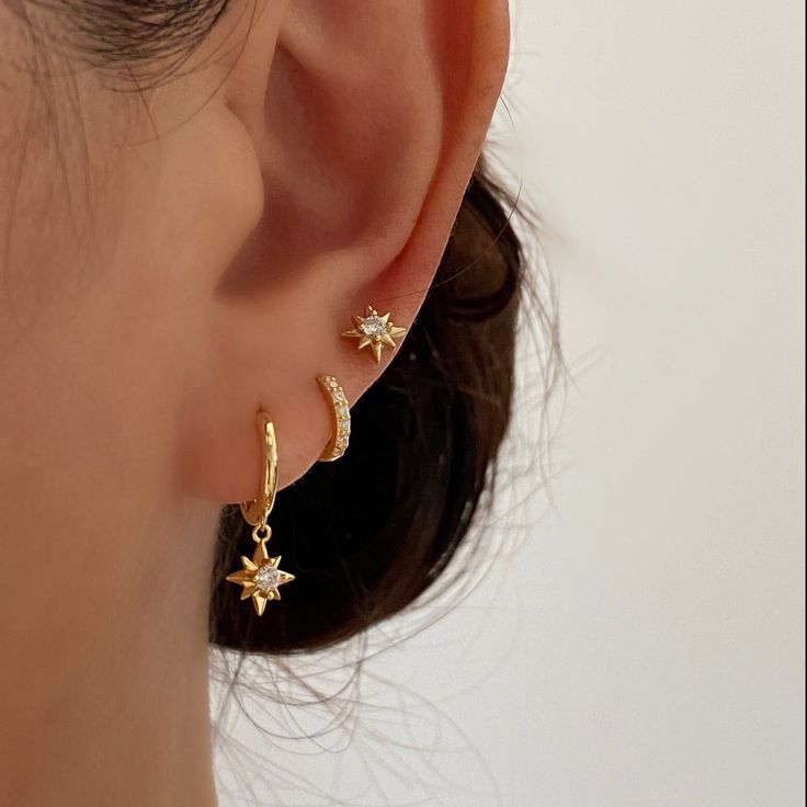 These Gorgeous dainty gold earrings are made of 925 sterling silver with 18k gold plated. They have beautifully crafted north star charms dangling from gold huggie hoop. Perfect for adding sparkle to your daily outfit. Beautifully go with the star stud earrings and basic gold huggies for ear stacking. A. Dangle earrings• Material: 18k Gold Plated on 925 sterling silver• Size: Length : 20mm , Hoop inner diameter: 8.5mm• Safe for sensitive skin• Can wear in the shower• Hypoallergenic, lead and nic Gold Constellation Piercings, Small Gold Dangle Earrings, Earring Inspiration Gold, Dainty Dangly Gold Earrings, Cartilage Piercing Ideas Minimalist, Cute Dainty Ear Piercings, Dainty Earrings Stack, Gold Jewelry For Hoco, Dainty Gold Hoop Earrings