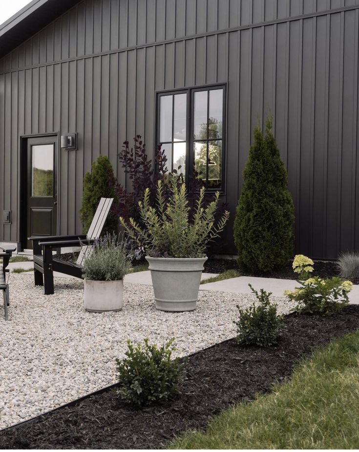 a house that has some plants in front of it and two chairs on the side