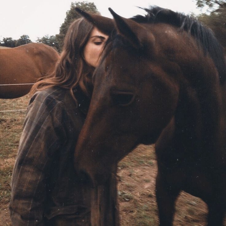 a woman standing next to a brown horse