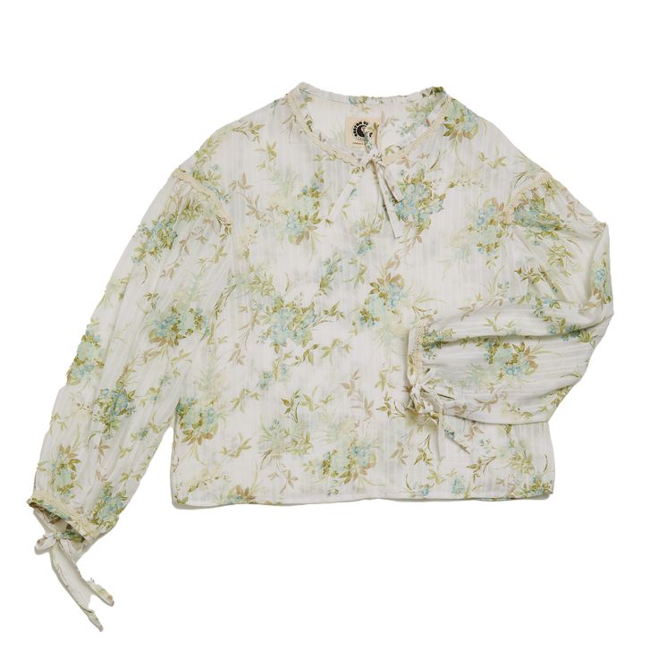 Crafted with meticulous care, each piece is unique, up-cycled from a soft fine vintage cotton fabric, ensuring both style and sustainability are at the forefront of your wardrobe.This one-of-a-kind shirt features long balloon sleeves adorned with intricate trim details, adding a touch of sophistication. The delightful floral pattern exudes a sense of nostalgic charm, making it a standout piece in any ensemble.Not stopping there, we've adorned this shirt with delicate bow ties at the neck and cuf Balloon Sleeve Floral Print Tops For Daywear, Spring Daywear Blouse With Balloon Sleeves, Spring Balloon Sleeve Blouse For Daywear, Cotton Floral Print Balloon Sleeve Top, Floral Print Balloon Sleeve Cotton Top, Spring Long Sleeve Blouse With Gathered Sleeves, Cotton Puff Sleeve Blouse With Smocked Cuffs, Cotton Blouse With Smocked Bishop Sleeves, Cotton Blouse With Smocked Cuffs And Puff Sleeves