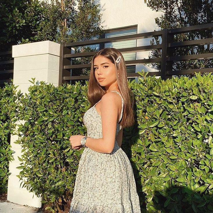 a woman standing in front of a hedge