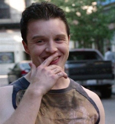 a man standing on the street with his hand under his chin and smiling at the camera