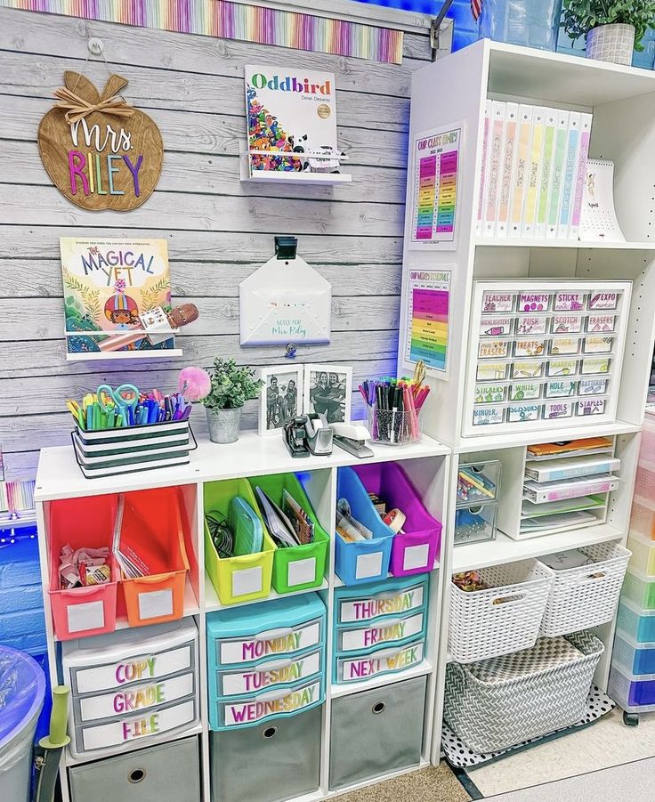 a room filled with lots of colorful bins next to a white book shelf covered in books