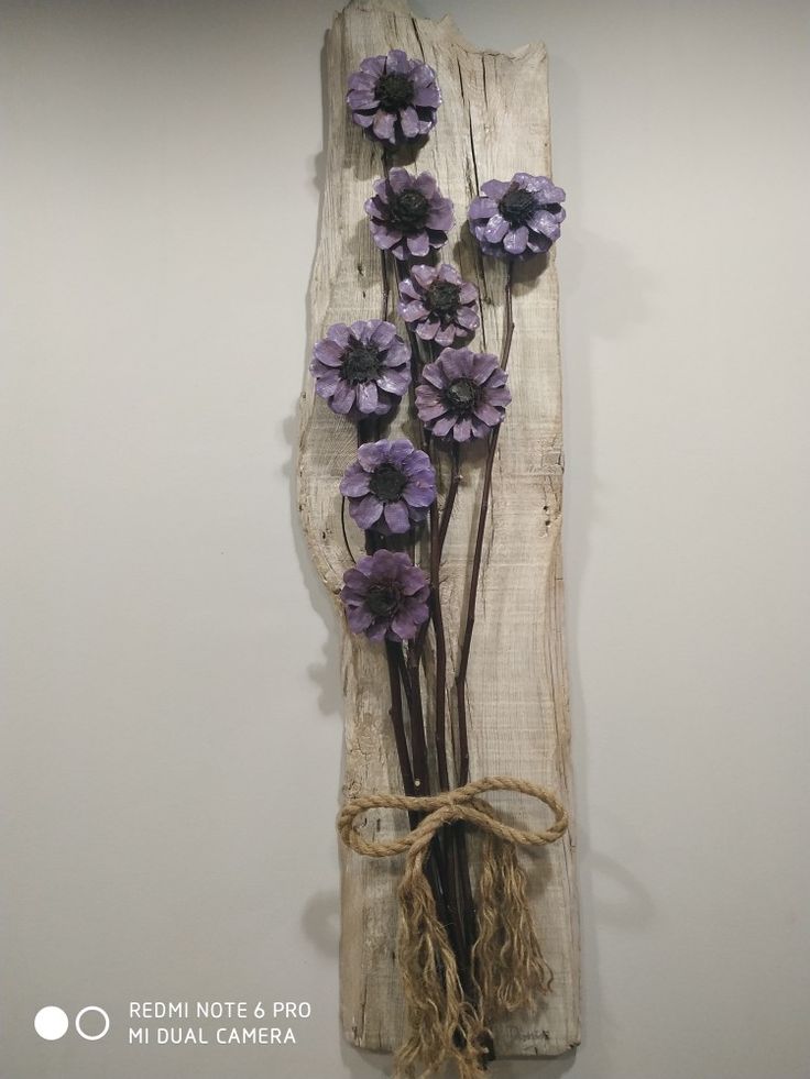 some purple flowers are tied to a piece of wood