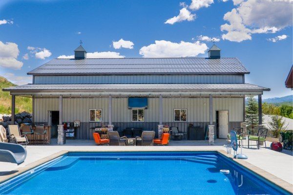 a house with a swimming pool in front of it and lounge chairs around the pool