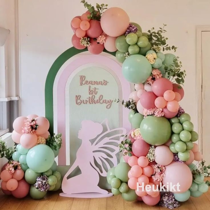 balloons and flowers decorate the entrance to a birthday party in pastel colors with a fairy silhouette