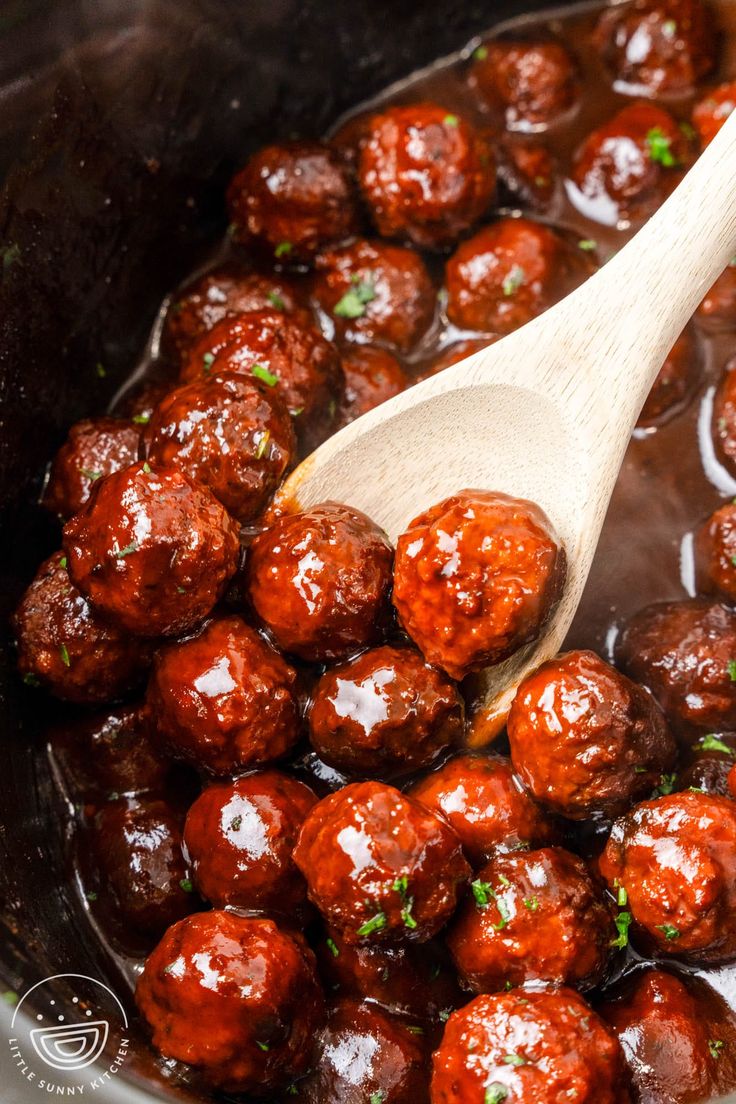 the meatballs are being cooked in the pot with a wooden spoon and is ready to be eaten