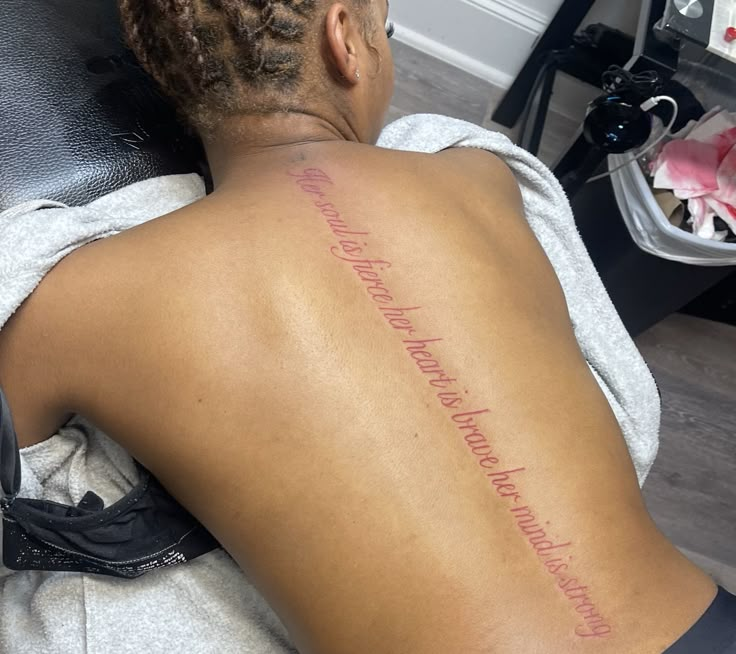 the back of a woman's upper body with writing on her left arm and chest