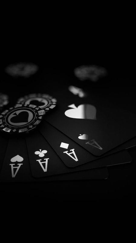 several playing cards are laying on top of each other in the dark, with white and black symbols all over them