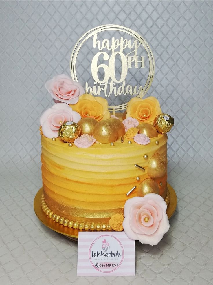 a yellow cake with pink flowers on top and a happy 60th birthday card next to it