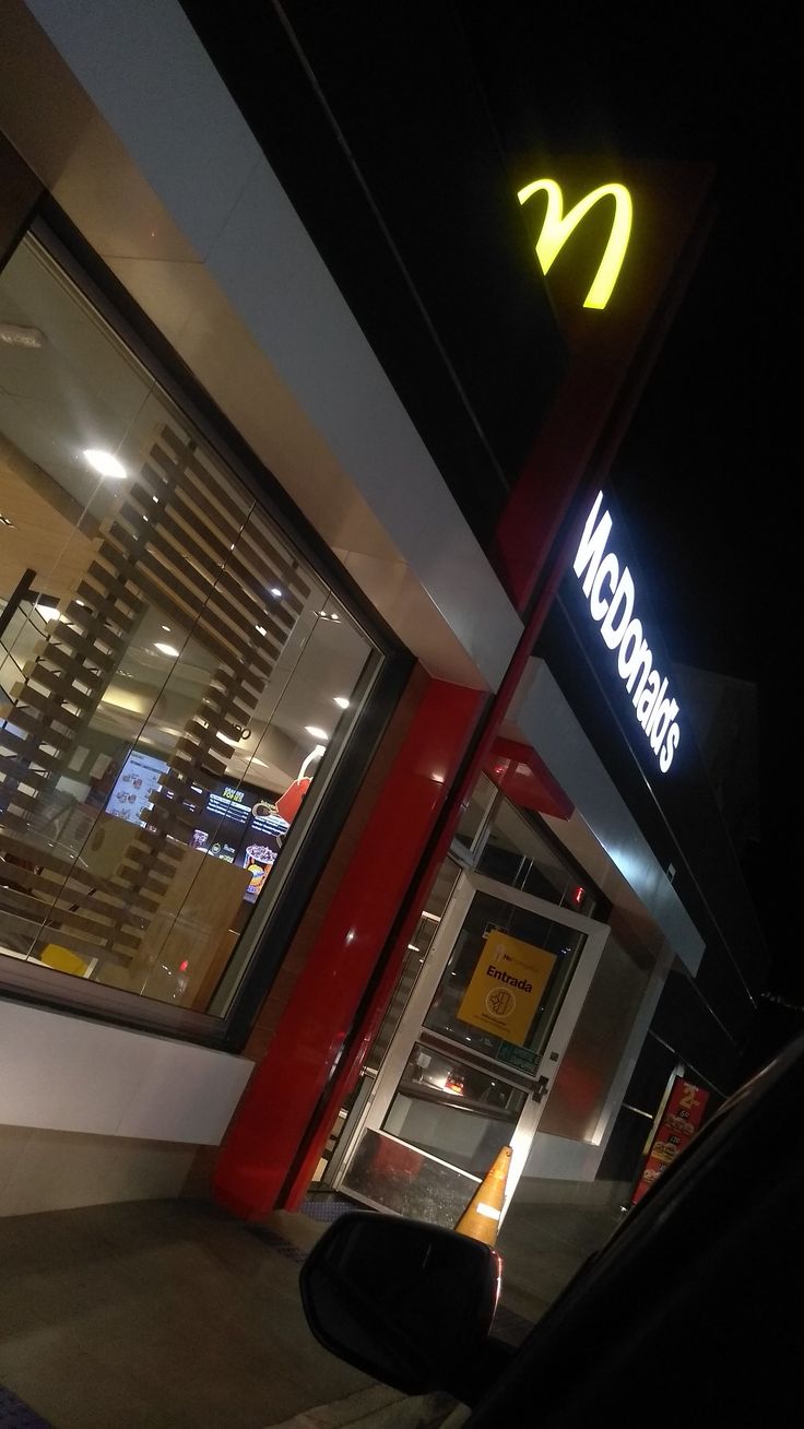 a mcdonald's restaurant at night with the neon sign lit up