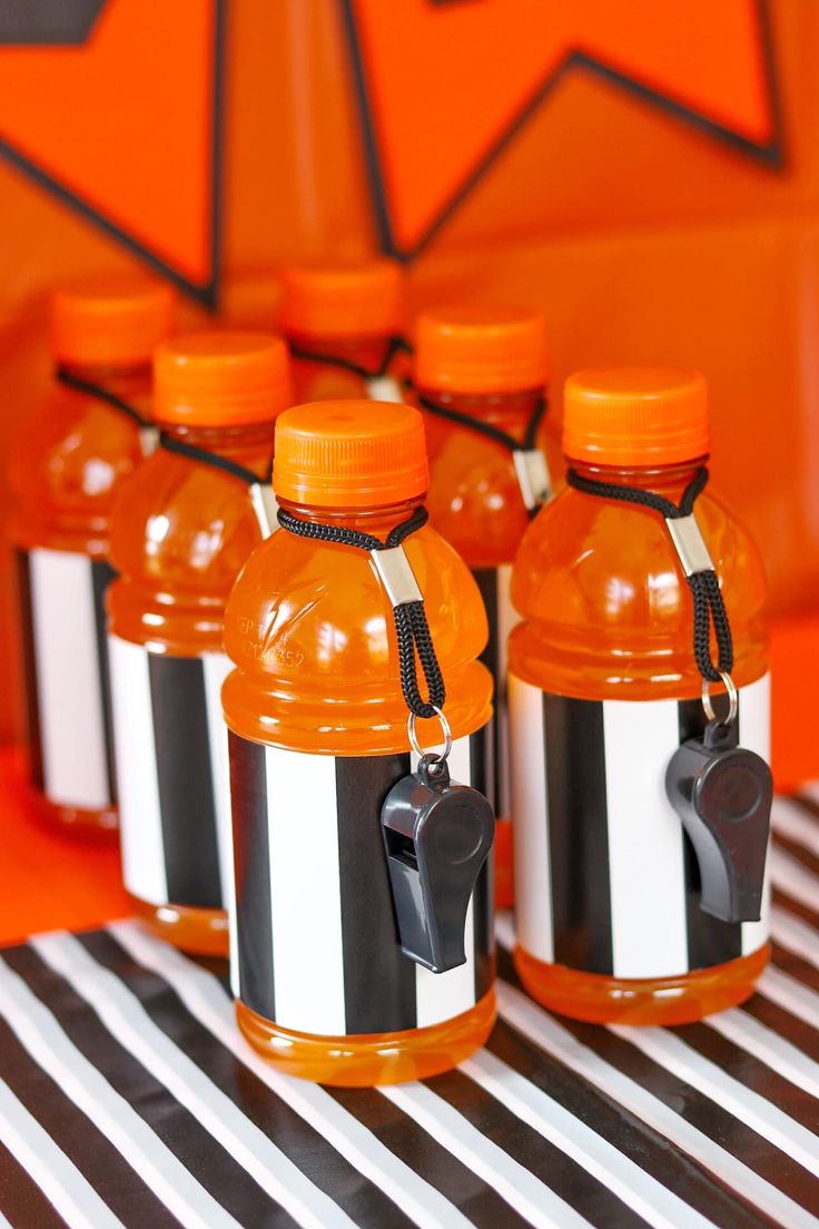 several orange and black water bottles on a striped tablecloth with an orange wall in the background