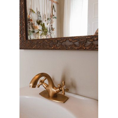 a bathroom sink with a gold faucet in front of a mirror above it