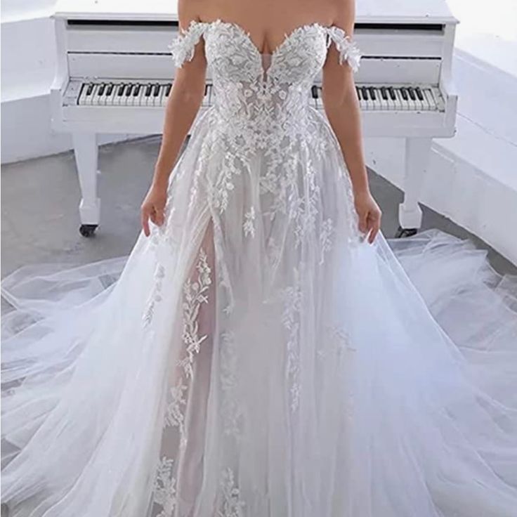 a woman standing in front of a piano wearing a white dress with flowers on it