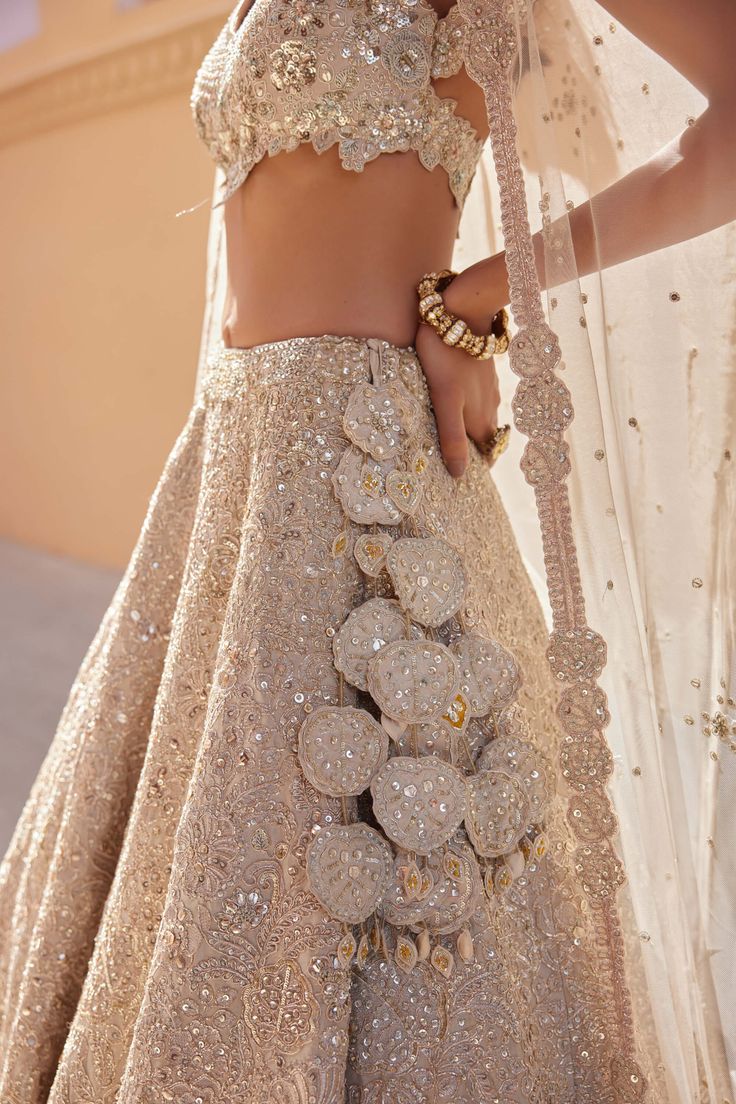 Step into timeless sophistication with our beige champagne embroidered lehenga, meticulously handcrafted with zardozi, french knots, aari work, and exquisite 3d floral embroidery. This stunning ensemble seamlessly blends traditional craftsmanship with modern elegance, perfect for weddings and special occasions. The soft beige champagne hue exudes understated luxury, while the intricate embroidery adds depth and charm to the lehenga. Ideal for those who appreciate meticulous detailing and timeles Luxury Lehenga For Eid Celebration, Luxury Elegant Lehenga For Eid, Luxury White Lehenga With Naqshi, Luxury Lace Work Lehenga For Eid, Luxury Party Choli For Eid, Luxury Georgette Lehenga For Wedding, Glamorous Luxury Choli With Dupatta, Luxury Semi-stitched Lehenga For Wedding, Luxury Semi-stitched Lehenga For Ceremony