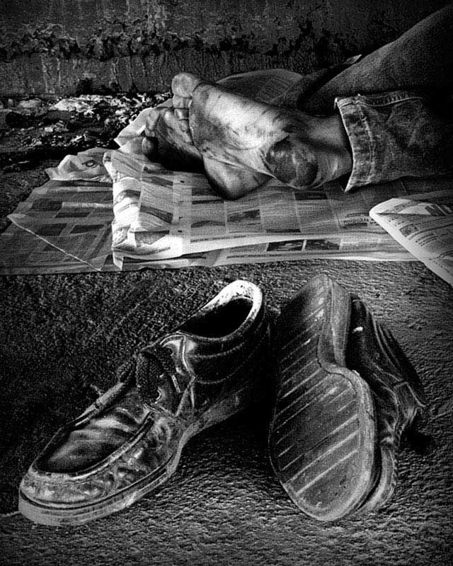 an old pair of shoes sitting on top of a floor next to a pile of newspapers