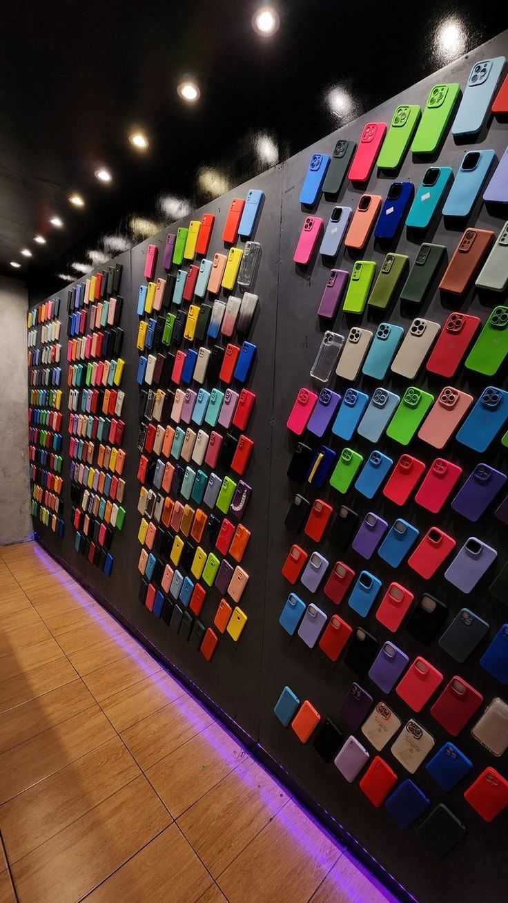 there are many cell phones on the wall in this room, all different colors and sizes