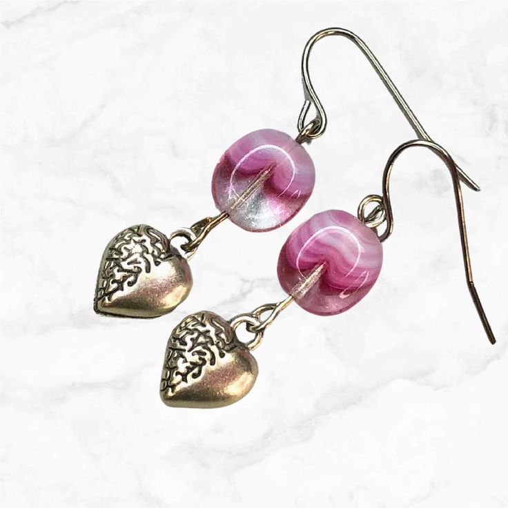 These exquisite small silver heart charm and pink glass dangle earrings are sure to capture hearts.  Puffy silver hearts beautifully complement pink Czech glass beads, adding a charming and vibrant pop of color to any outfit.  The pink and white Czech glass beads are made of clear glass infused with pink glass; each bead is different and special. Just beautiful.  Hypoallergenic ear wires (nickel and lead free). Choose ear wires at checkout. A gift for you or someone special, earrings are carded Heart Beads Metal Earrings For Gift, Heart Beaded Metal Earrings As Gift, Metal Heart Beads Earrings For Gifts, Metal Heart Beaded Earrings For Gifts, Heart Beads Metal Earrings As Gift, Adjustable Heart Beads Dangle Earrings, Metal Heart Bead Earrings As Gift, Gift Metal Heart Earrings With Heart Beads, Elegant Heart Beads Earrings