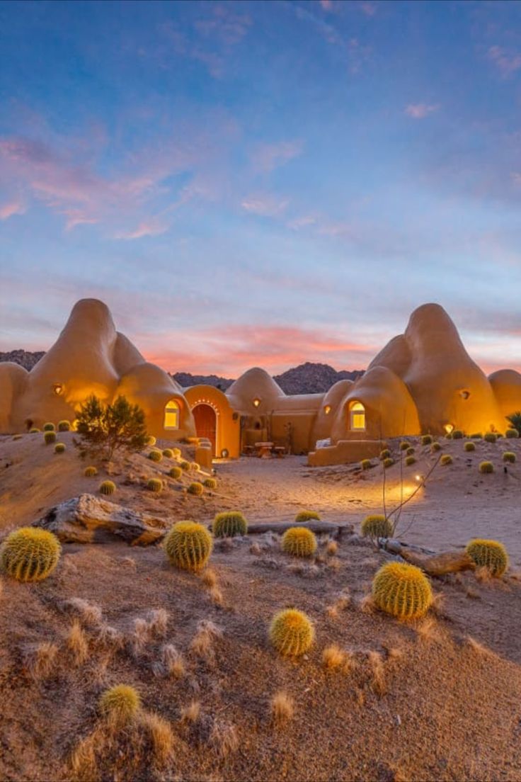 an adobe - style house sits in the desert at dusk