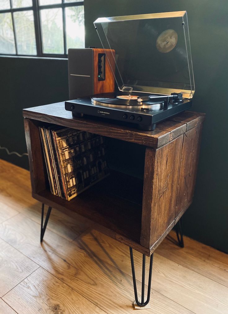 an old record player is sitting on top of a wooden table with hairpin legs