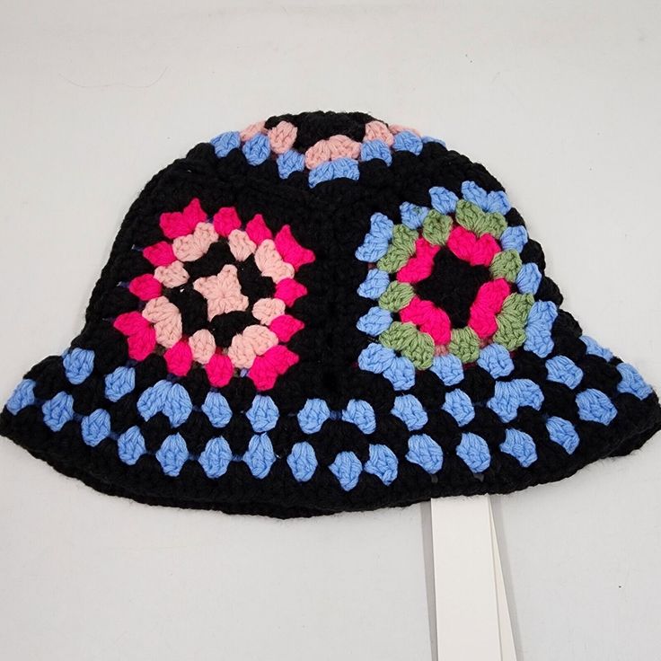 a crocheted black hat with pink, blue, and green flowers on it