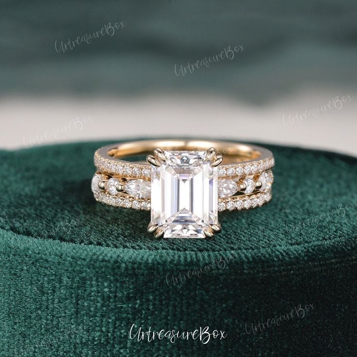 an emerald colored diamond engagement ring set on top of a green velvet box