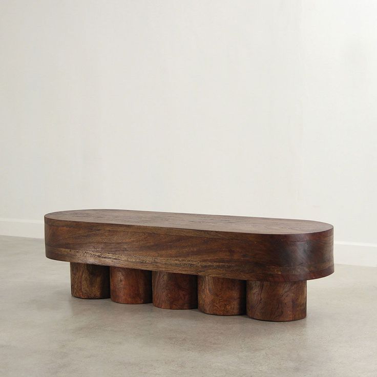 a wooden bench sitting on top of a cement floor next to a white wall in an empty room