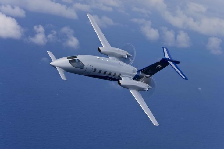 an airplane flying in the sky with clouds behind it and blue water below on both sides