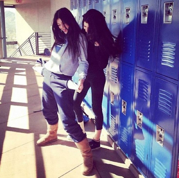 two young women leaning against lockers in the sun