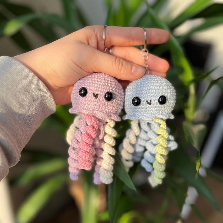 two little crocheted octopus key chains being held by someone's hand