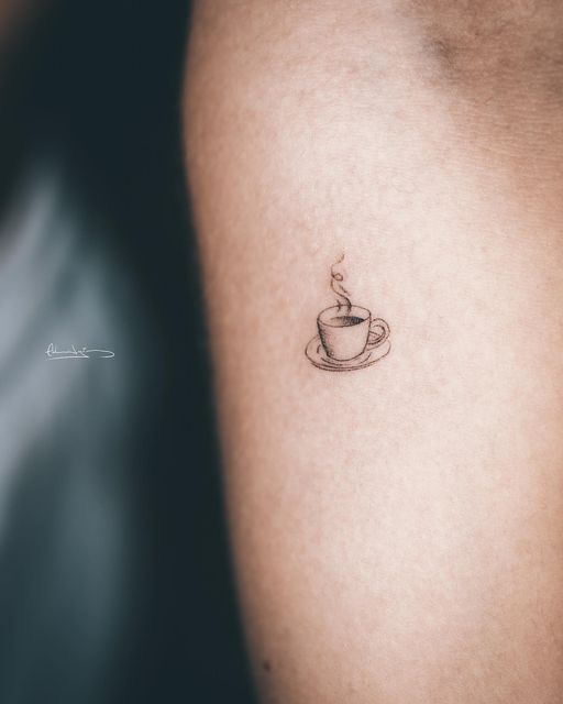 a small coffee cup tattoo on the left side of the right arm is shown in black and white