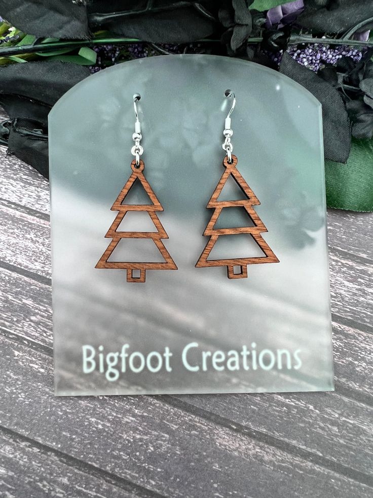 the earrings are made from wood and have wooden triangles on them, as well as words that read bigfoot creations