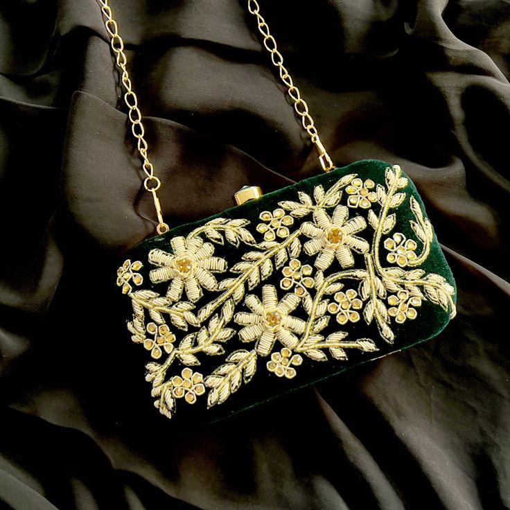 Dark green box clutch, adorned with luxurious gold and silver tones and Golden Metallic Frame. Crafted from plush velvet fabric, this clutch comes with a detachable shoulder strap, providing versatility in how you carry it and durable lining. The intricate embellishments and zardosi work showcase the skilled craftsmanship of Indian artisans, making each piece a unique work of art. Specifications: Main Compartment: The clutch features a single spacious compartment, providing enough room for your