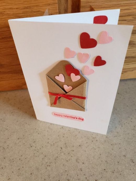 a greeting card with hearts coming out of an envelope on a countertop next to a wooden door