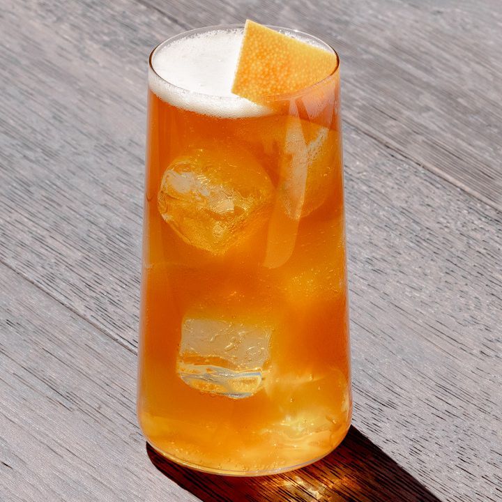 a tall glass filled with orange juice and ice