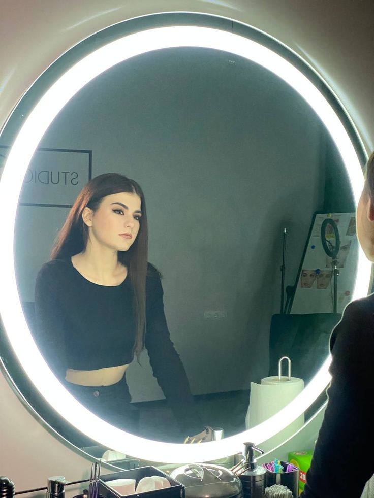 a woman standing in front of a round mirror