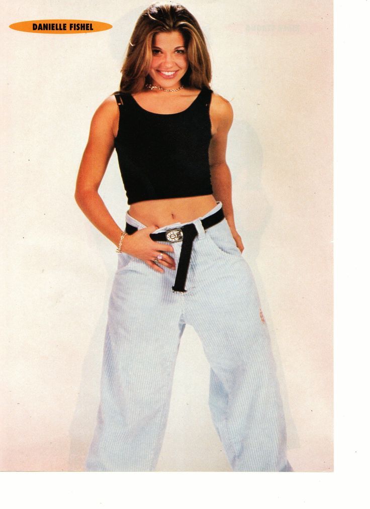 a woman is posing for the camera with her hands on her hips and wearing wide pants