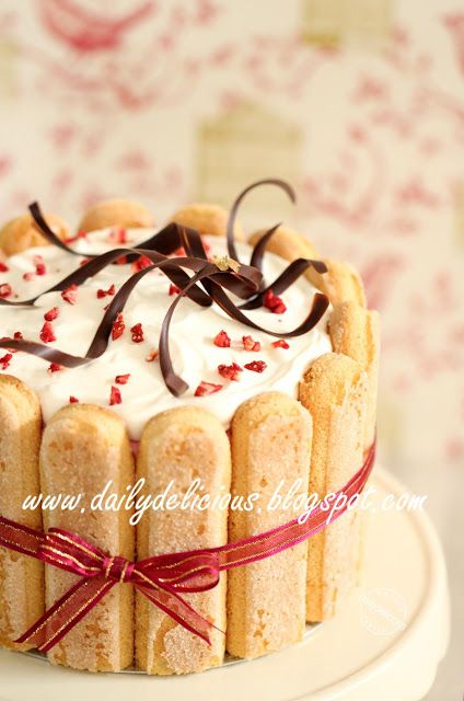 a cake with white frosting and red sprinkles on top sitting on a plate