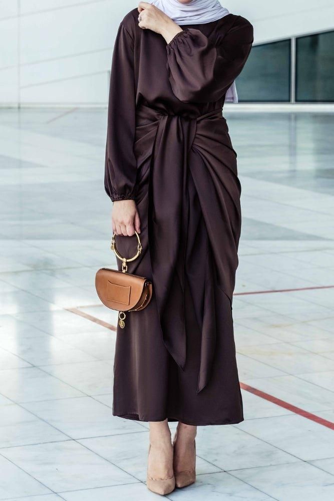 Introducing the Ohlivia Maxi Abaya Dress in rich dark chocolate, crafted with a blend of satin and polyester for a luxurious and comfortable experience. The dress features a detached apron with elasticated sleeves, a tie waist piece, and a flattering pattern that is not oversized. With its versatility, you can wear it front knotted or sideway, adjusting the fit with the apron. To ensure the perfect fit, please refer to the size chart in the next slides, and note that smaller sizes have a shorter Elegant Satin Maxi Abaya, Brown Satin Maxi Length Dress, Elegant Brown Satin Maxi Dress, Formal Brown Satin Maxi Dress, Elegant Long Sleeve Brown Abaya, Elegant Long Brown Abaya, Modest Long Brown Maxi Dress, Eid Satin Maxi Dress, Modest Activewear