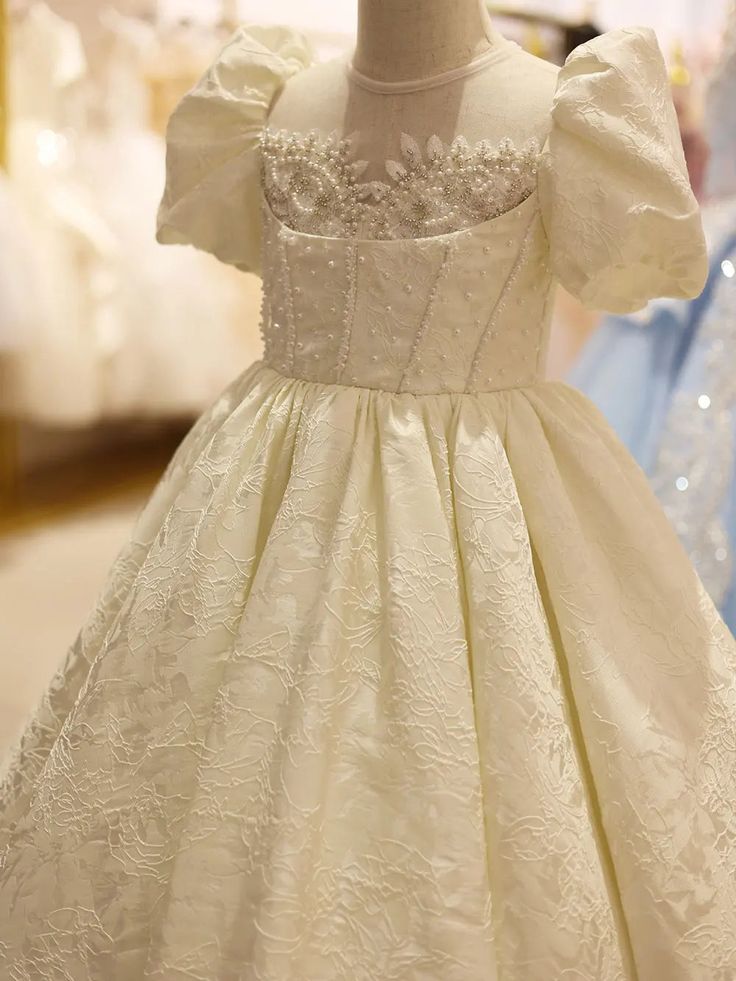 Indulge in elegance with Dreamy Vow's luxury white flower girl dress. Adorned with intricate beading and puffed sleeves, this formal gown is the perfect addition to weddings, birthdays, and pageants. Make your little one's special day even more magical with J092. Elegant Princess Dress With Pearl Embroidery For Baptism, Elegant Princess Dress With Fitted Bodice For Pageants, Elegant Puff Sleeve Princess Dress For Wedding, White Puff Sleeve Dress For First Communion, Elegant White Princess Dress With Fitted Bodice, Elegant Princess Dress With Fitted Bodice For First Communion, Elegant Cream Princess Dress For Wedding, White Embellished Princess Dress, Elegant Fitted Princess Dress With Puff Sleeves