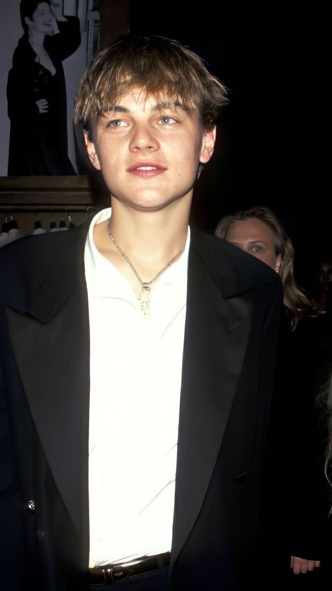 a young man wearing a black suit and white shirt