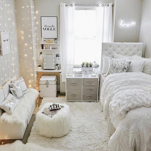 a bedroom decorated in white and silver with lights on the walls, bedding, rugs and pillows