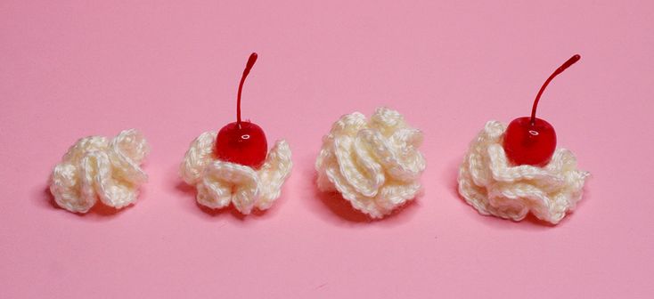 three crocheted cherries on a pink background