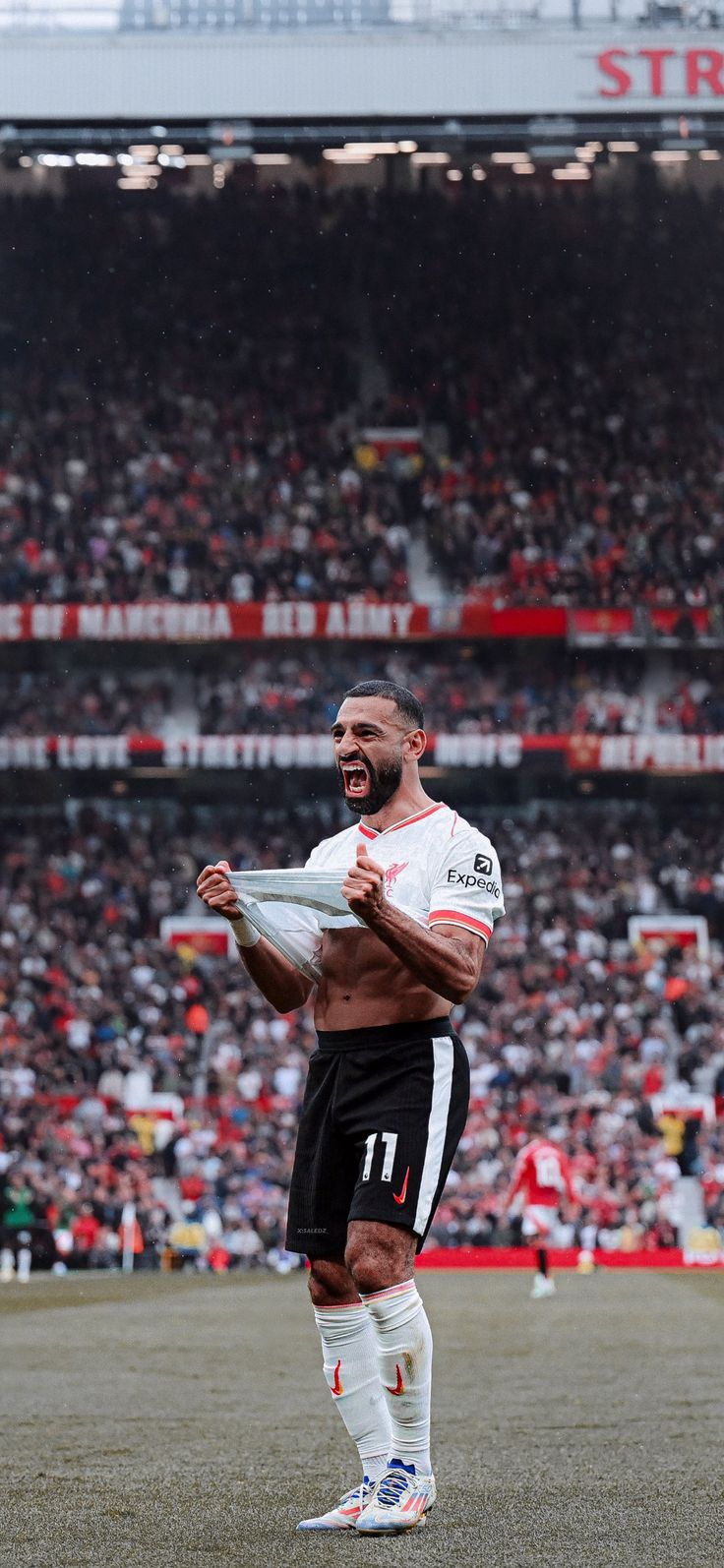 a man holding a soccer ball on top of a field in front of a crowd