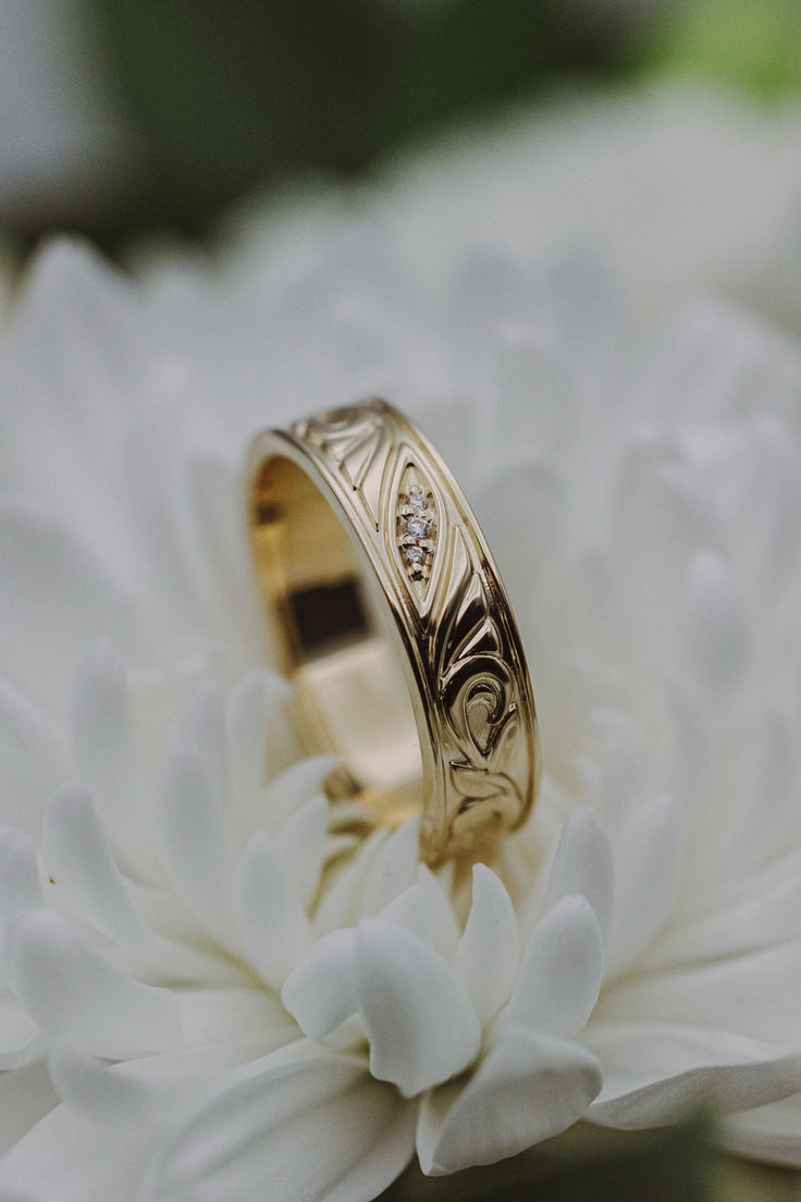 A 14K yellow gold mens' engagement band sits on a white chrysanthemum flower. This band features floral filigree details and three diamond accents. White Gold Engagement Rings For Men, Nature Inspired Wedding Ring Men, Mens Wedding Rings Unique Diamonds, Custom Wedding Bands For Men, Wedding Groom Ring, Wedding Band For Men Gold, Unique Engagement Rings For Men Future Husband, Unique Engagement Rings For Men For Him, Unique Mens Jewelry