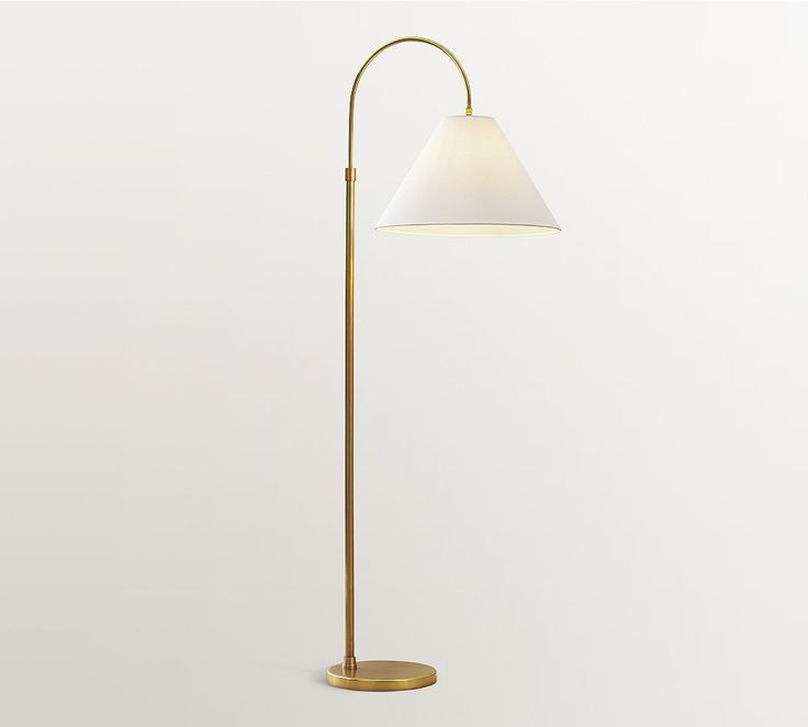 a floor lamp with a white shade on the base and a gold plated stand