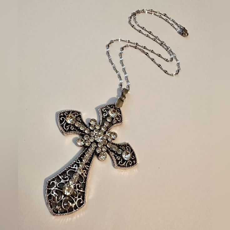 Silver Gothic Cross Necklace Beautiful Statement Piece, Gothic Cross Pendant Embedded With Sparkling Cubic Zirconia Gemstones On A Stainless Steel Chain. *Chain Length: 45cm. *Chain Material: Stainless Steel. *Cross Pendant Length:75cm * Ready To Ship Next Day * If You Are Interested In More Than One Item From My Store Pleased Message Me To Make A Bundle For You With Combined Shipping. #Bigcross #Crystaljewelry #Rosarynecklace #Crossnecklace #Grungenecklace Tags: Gothic Cross Necklace Handmade Jewelry Handmade Necklace Crystal Jewelry Crystal Necklace Cottage Core Earthcore Boho Jewelry Wicca Witchy Occult Fae Whimsigoth Coquette Rosary Grunch Cross Necklace Silver Cross Big Cross Vic Nickel-free Gothic Necklaces For Party, Gothic Metal Cross Pendant Jewelry, Metal Cross Pendant Necklace With Rhinestones, Gothic Cross Pendant Jewelry, Metal Rhinestone Cross Pendant Necklace, Handmade Punk Style Cross Jewelry, Silver Cross Pendant Jewelry For Halloween, Gothic Cross Necklaces For Jewelry Making, Gothic Metal Cross Necklaces