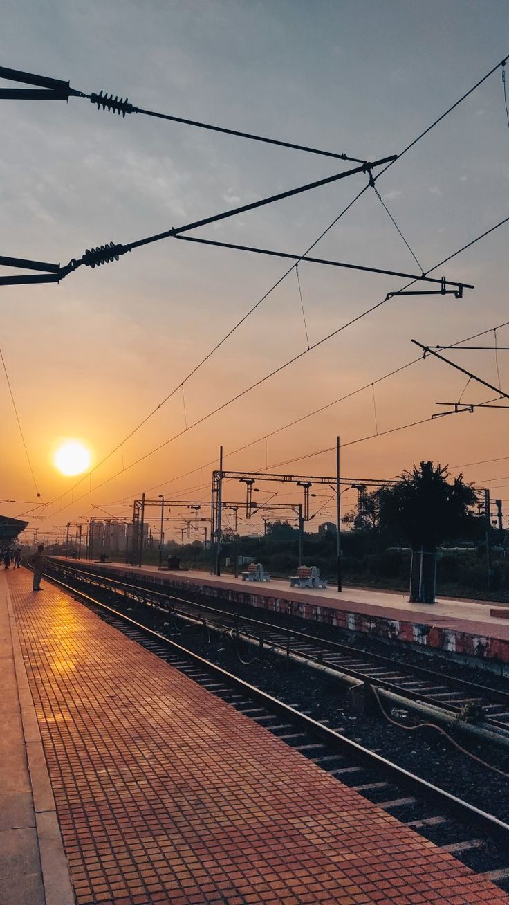 the sun is setting over an empty train station